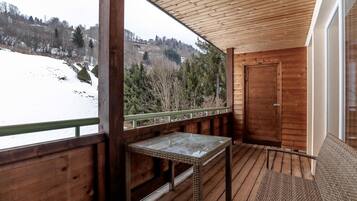 Un balcon en bois donnant sur un paysage enneigé, avec une porte.