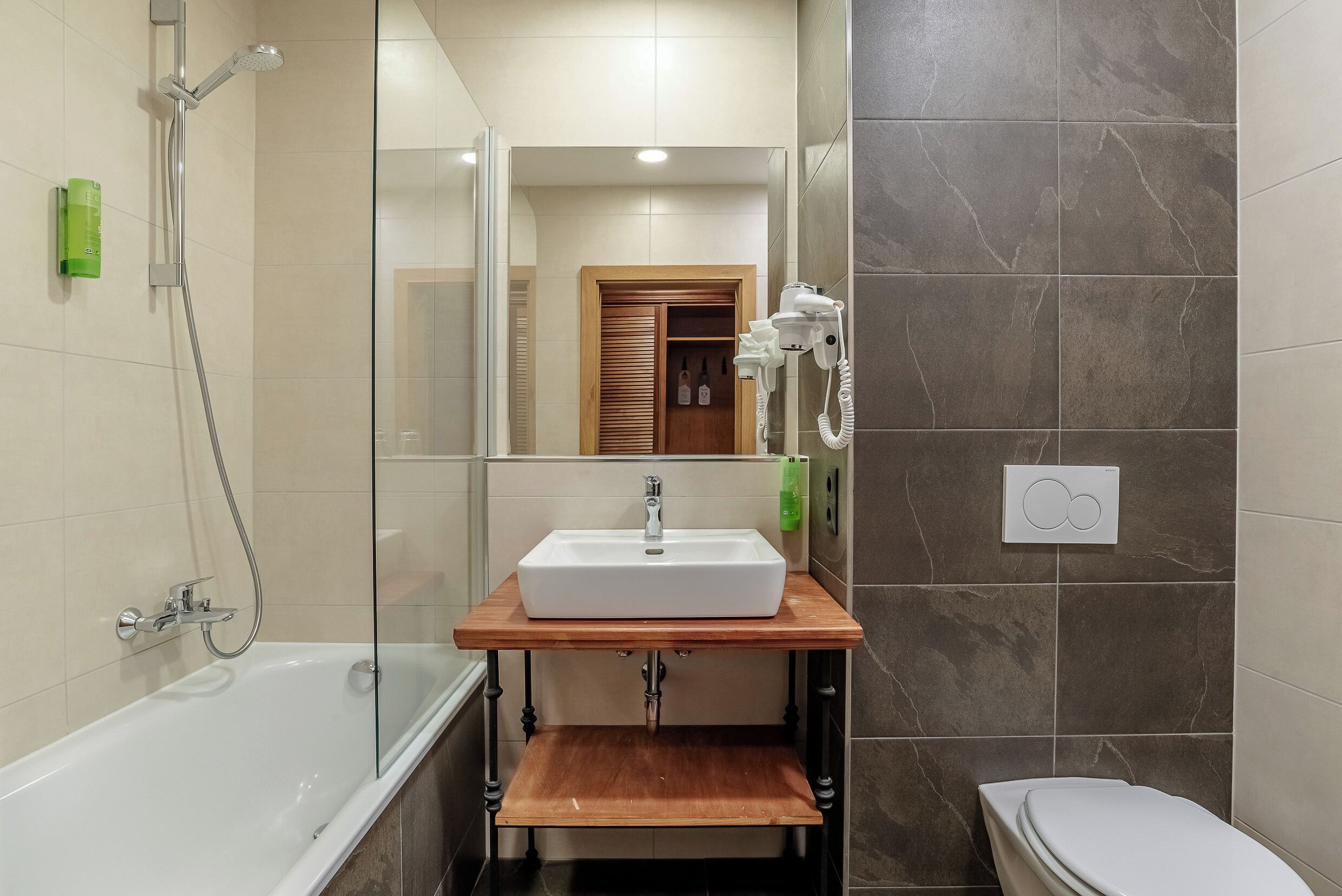 A bathroom with a bathtub, a sink, a mirror, and a toilet.