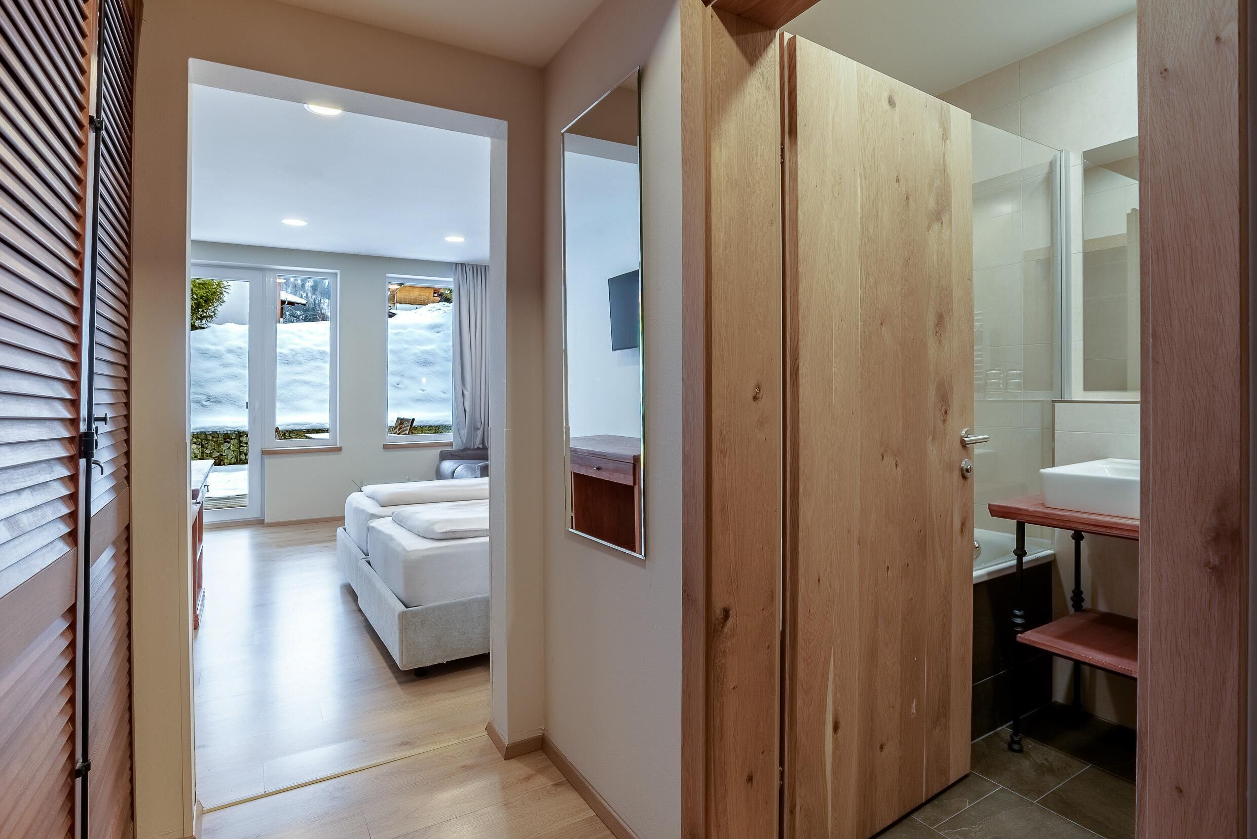 Un baño moderno con puerta de madera, lavamanos blanco y espejo.