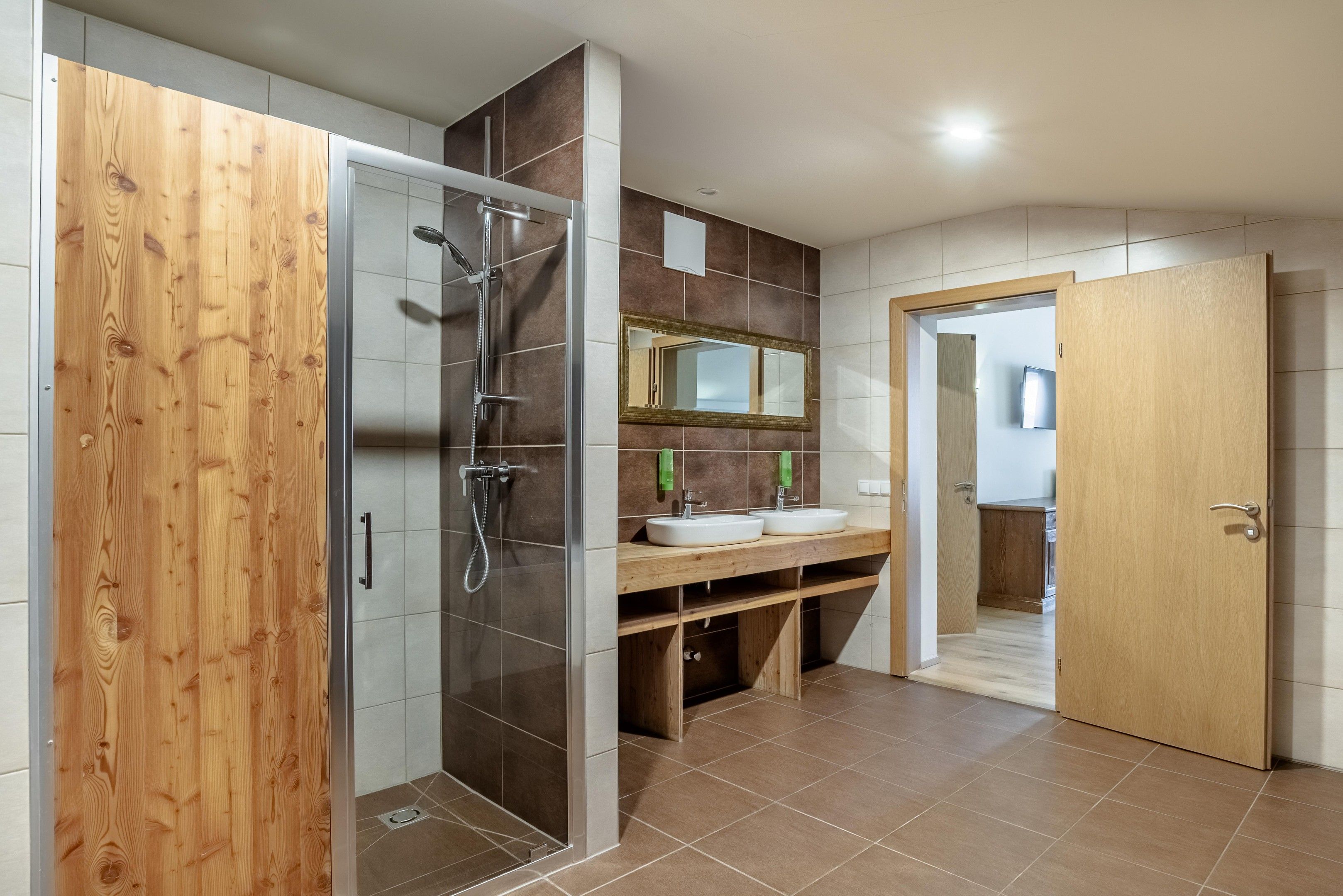 A modern bathroom with a glass shower enclosure, wooden vanity, and a mirror above the sink.