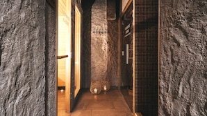 A hallway with stone walls, wooden doors, and tiled flooring.