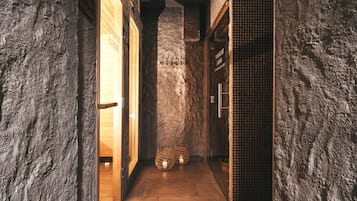 Un pasillo con paredes de piedra, puertas de madera y suelo de baldosas.
