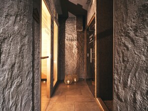 A hallway with stone walls, wooden doors, and tiled flooring. - Hotel Victoriya (Kaprun)