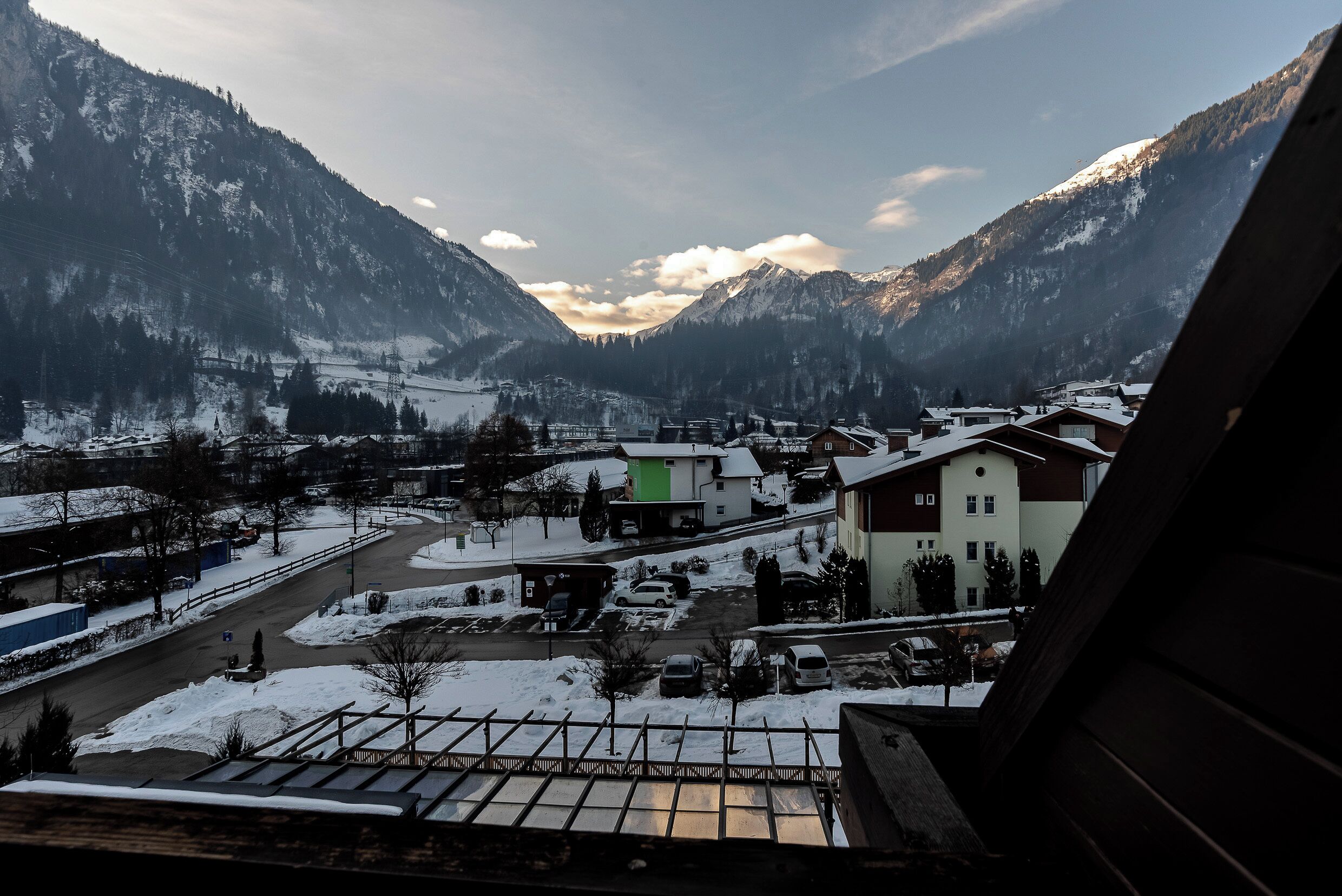 Un village de montagne aux rues et aux bâtiments recouverts de neige, entouré de montagnes.