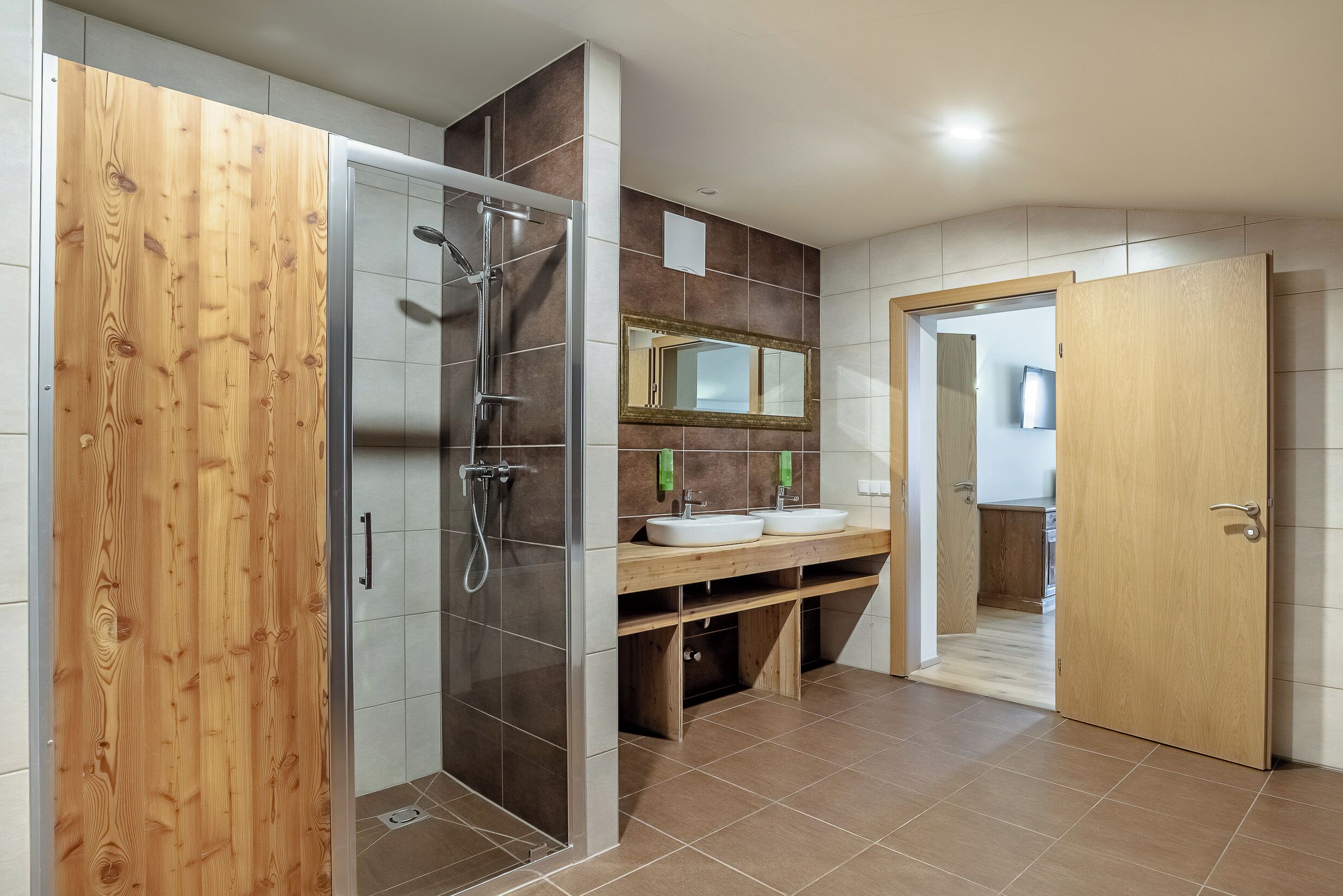 Ein modernes Badezimmer mit Dusche, einem Holzwaschtisch, einem Spiegel und einem Waschbecken.