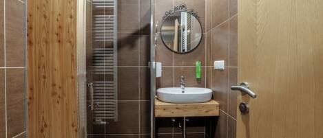 Une salle de bain avec une porte en bois, un lavabo, un miroir et un porte-serviettes.
