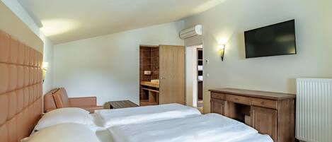 Un dormitorio con cama, escritorio, armario y televisor.