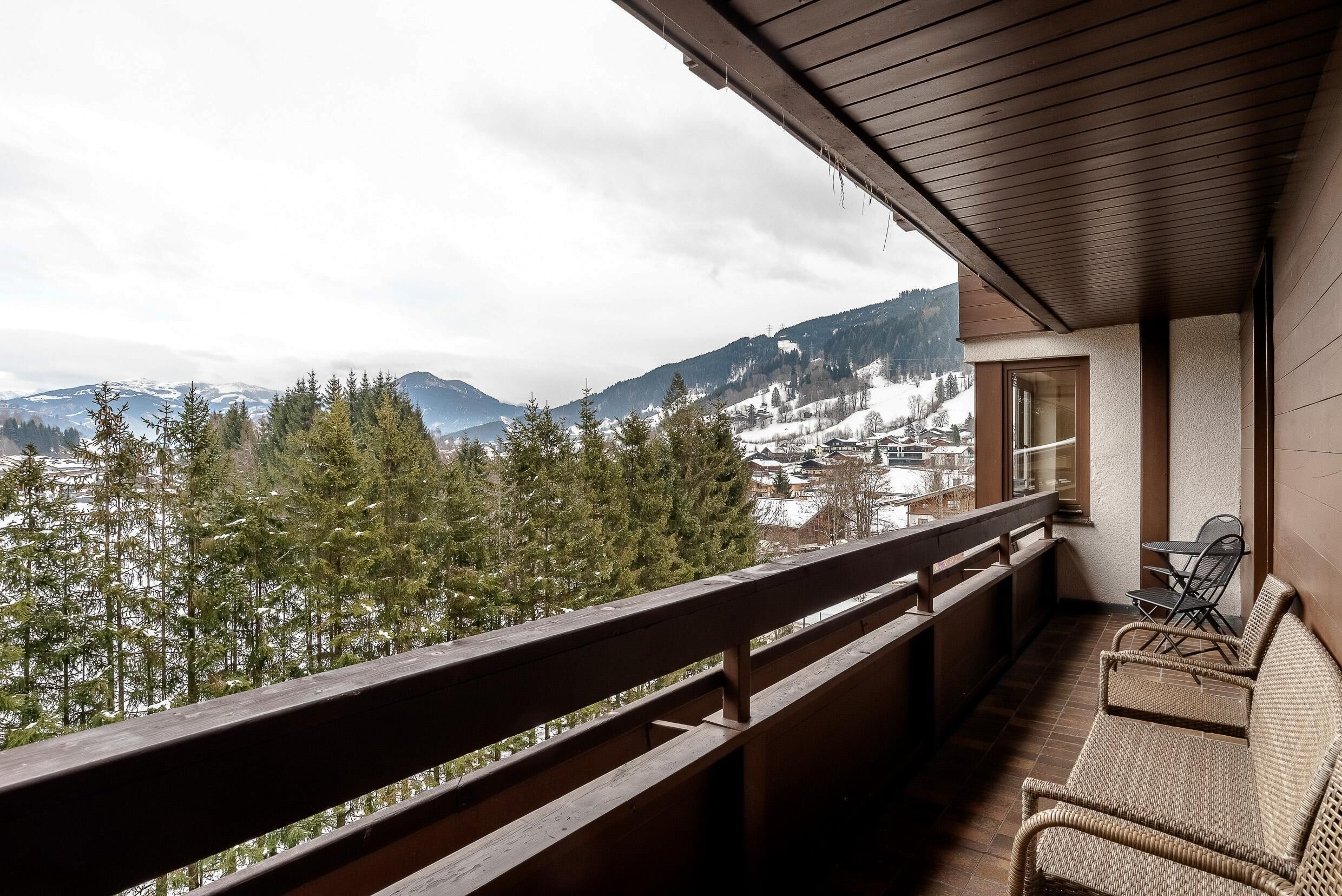 A balcony with a view of snow-covered mountains and trees.