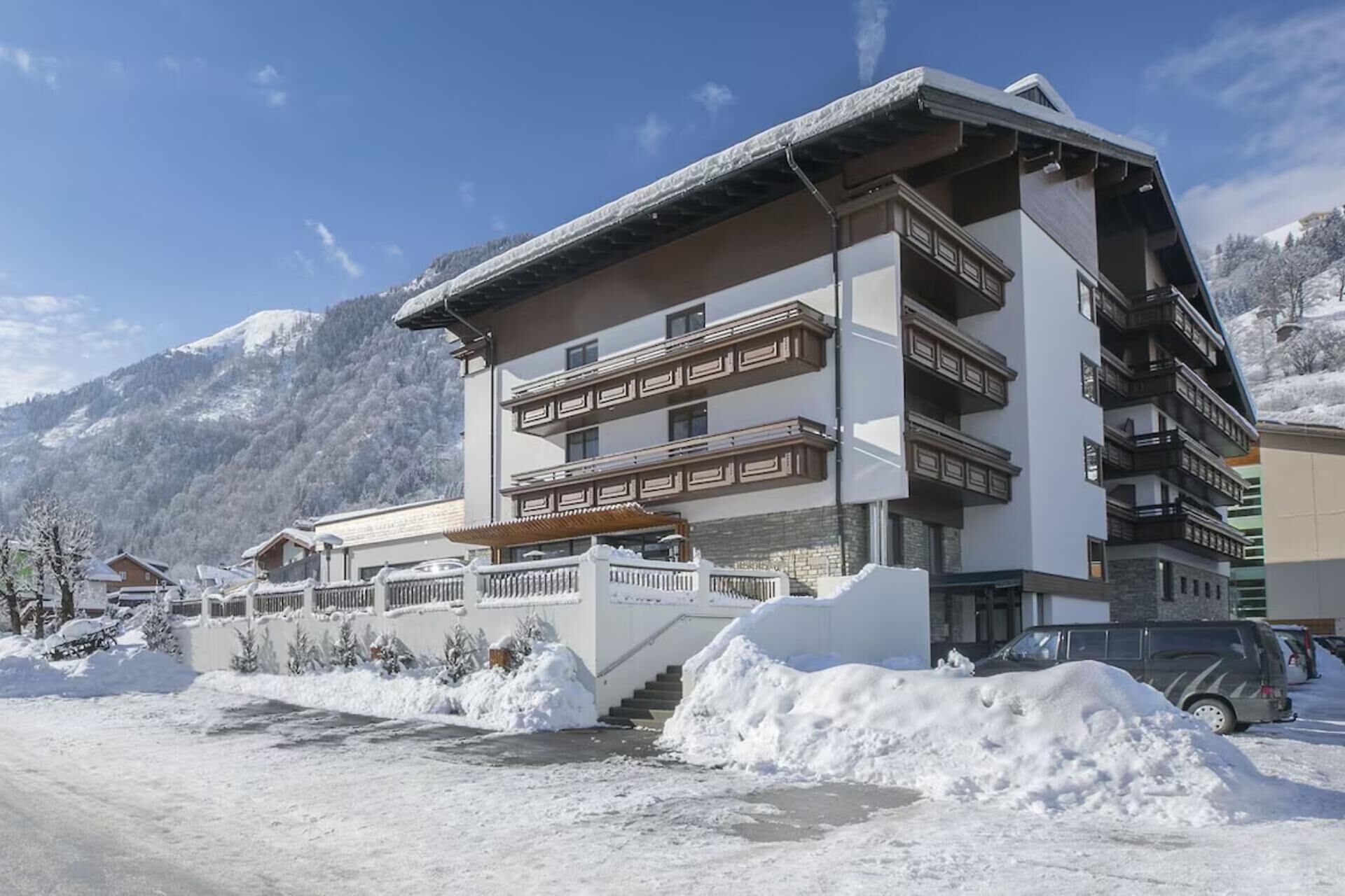 Un hôtel à plusieurs étages doté de balcons, un paysage enneigé et des montagnes en arrière-plan.