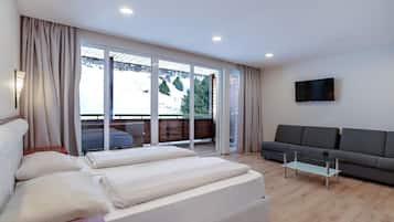 Una sala moderna con un sofá, una mesa de centro de vidrio y una cama con almohadas.