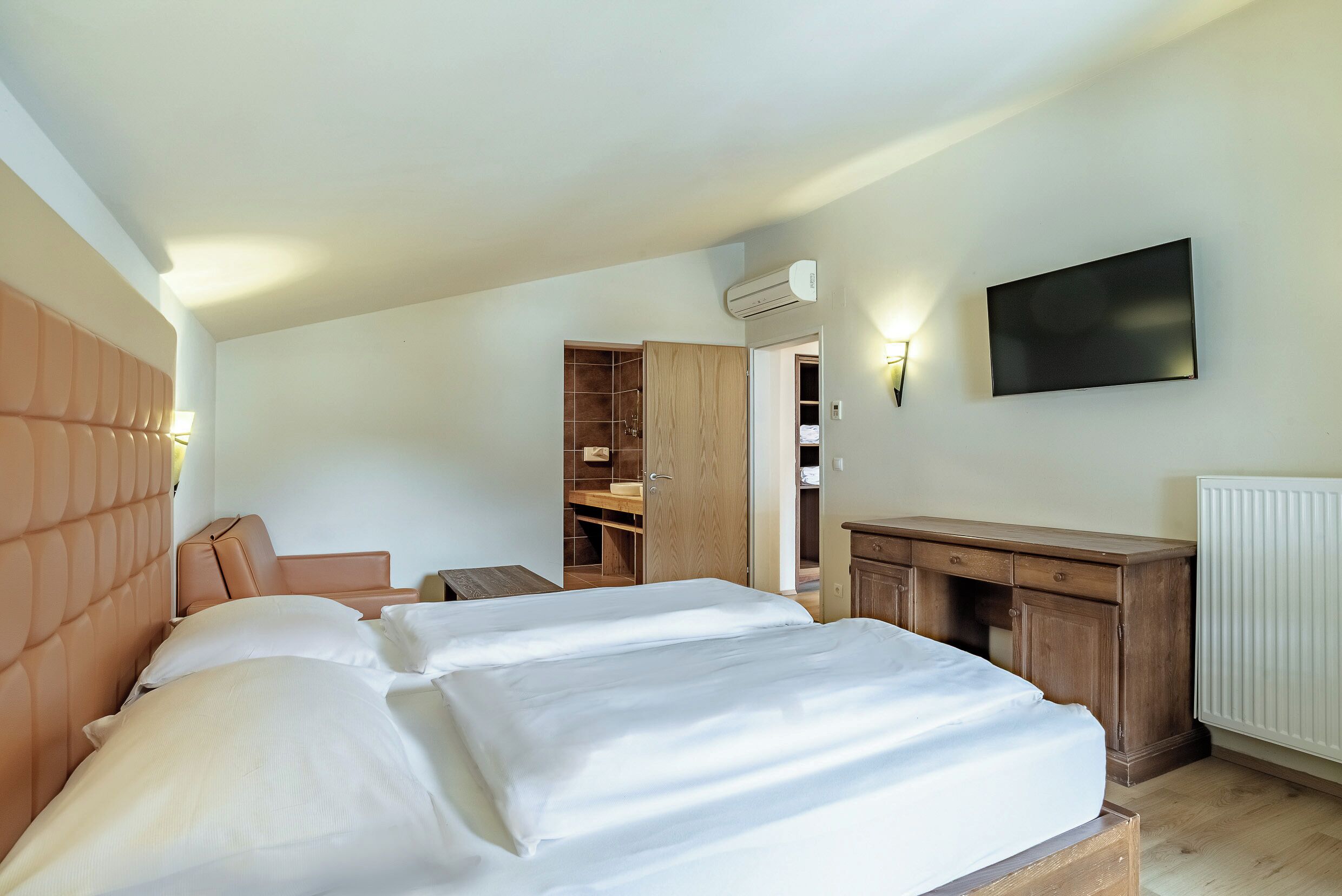 Une chambre à coucher avec un lit, un bureau, une armoire et un téléviseur.