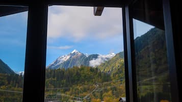 Paisagem de montanha com uma cabana e uma casa em primeiro plano, e a moldura de uma janela de trem.