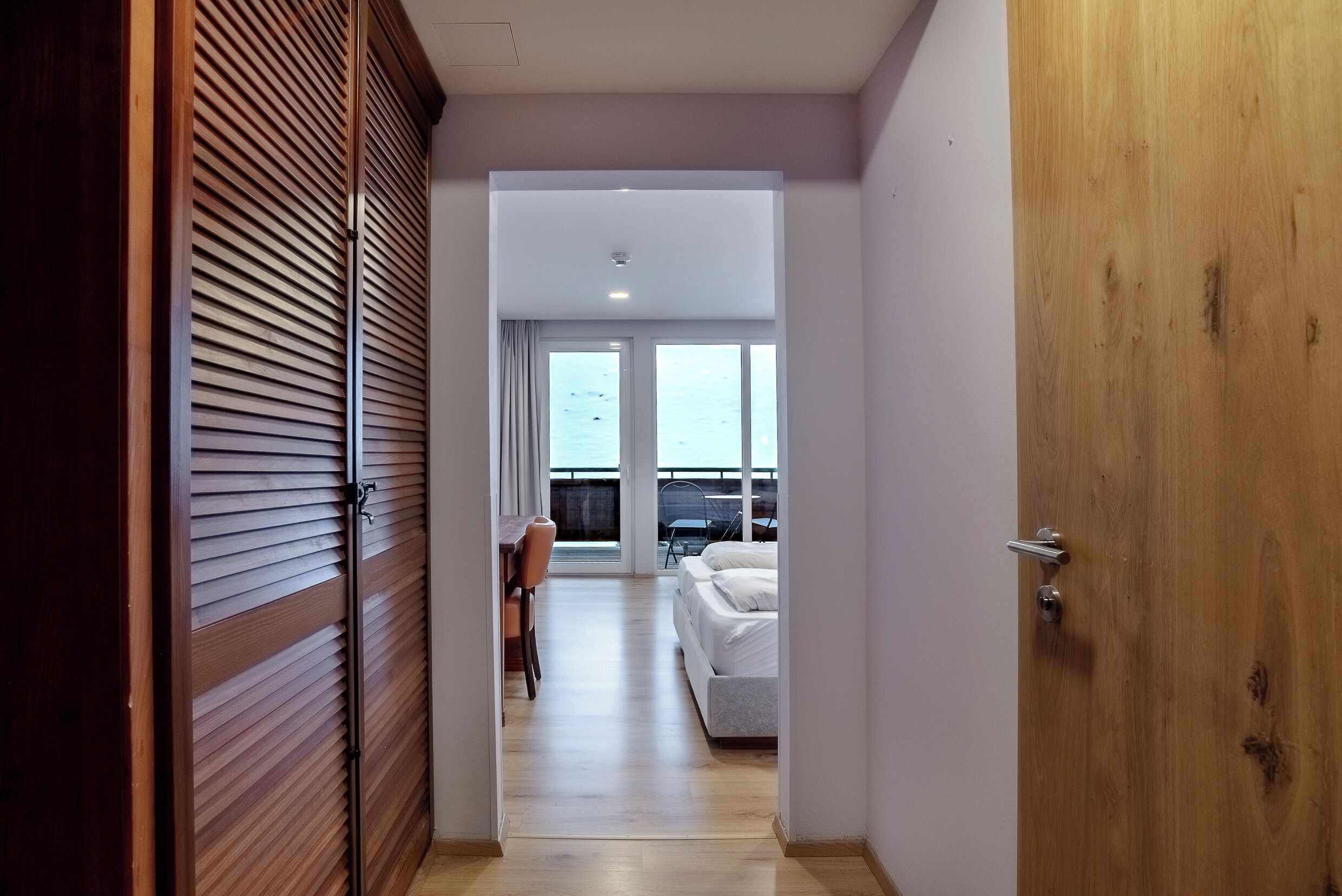 Un couloir d’hôtel menant à une chambre avec vue sur la mer.
