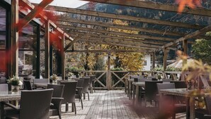 An outdoor patio with wicker furniture and a wooden deck. - Hotel Victoriya (Kaprun)