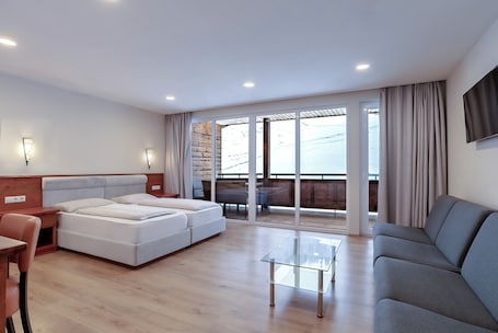 Une chambre d’hôtel moderne équipée d’un lit, d’un canapé, d’une table basse en verre et d’un balcon avec vue.. Hotel Victoriya