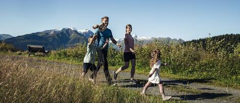 Una familia caminando por un sendero de grava con montañas al fondo.