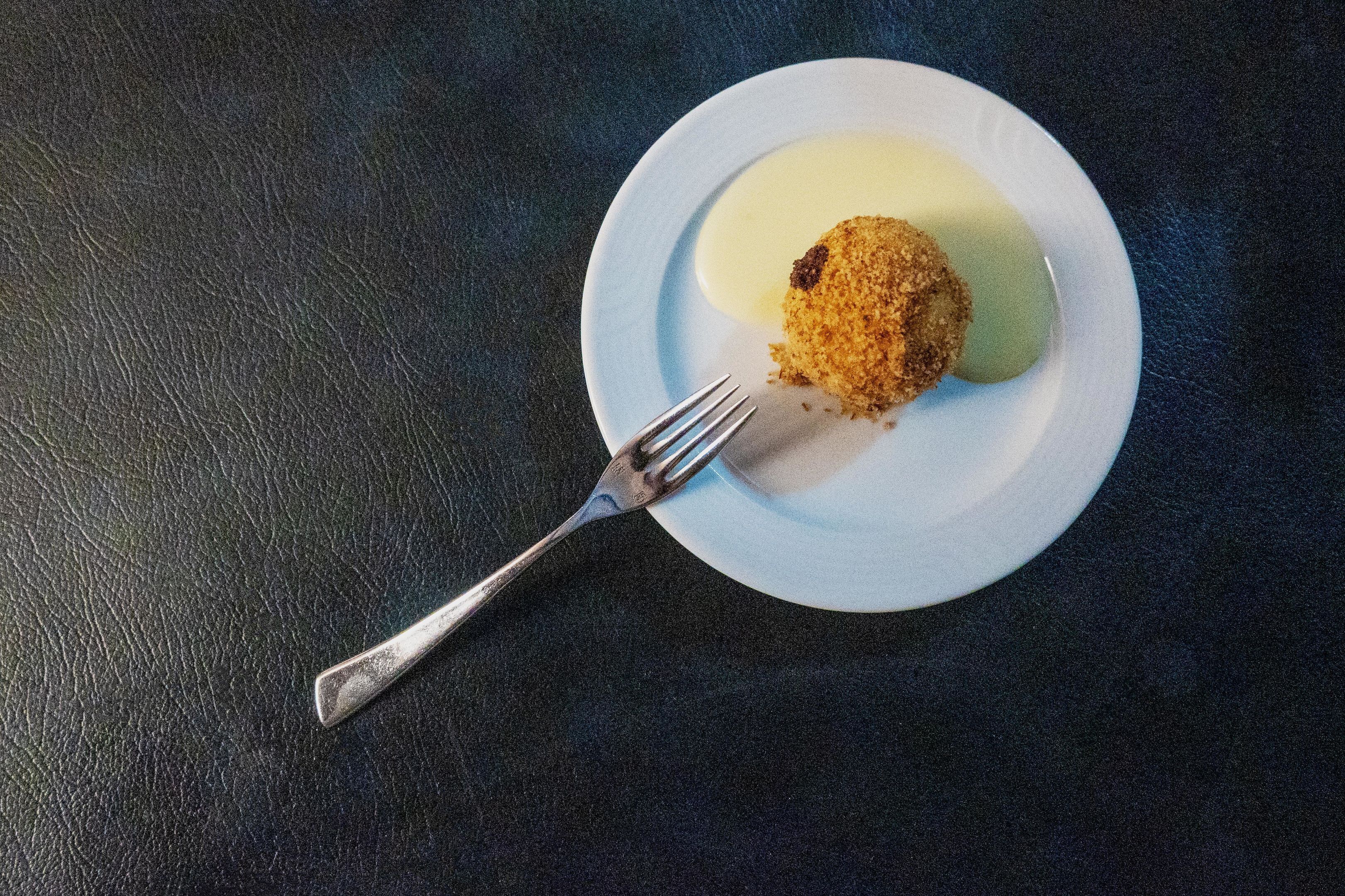 A plate with a food item and a fork on a dark textured surface.