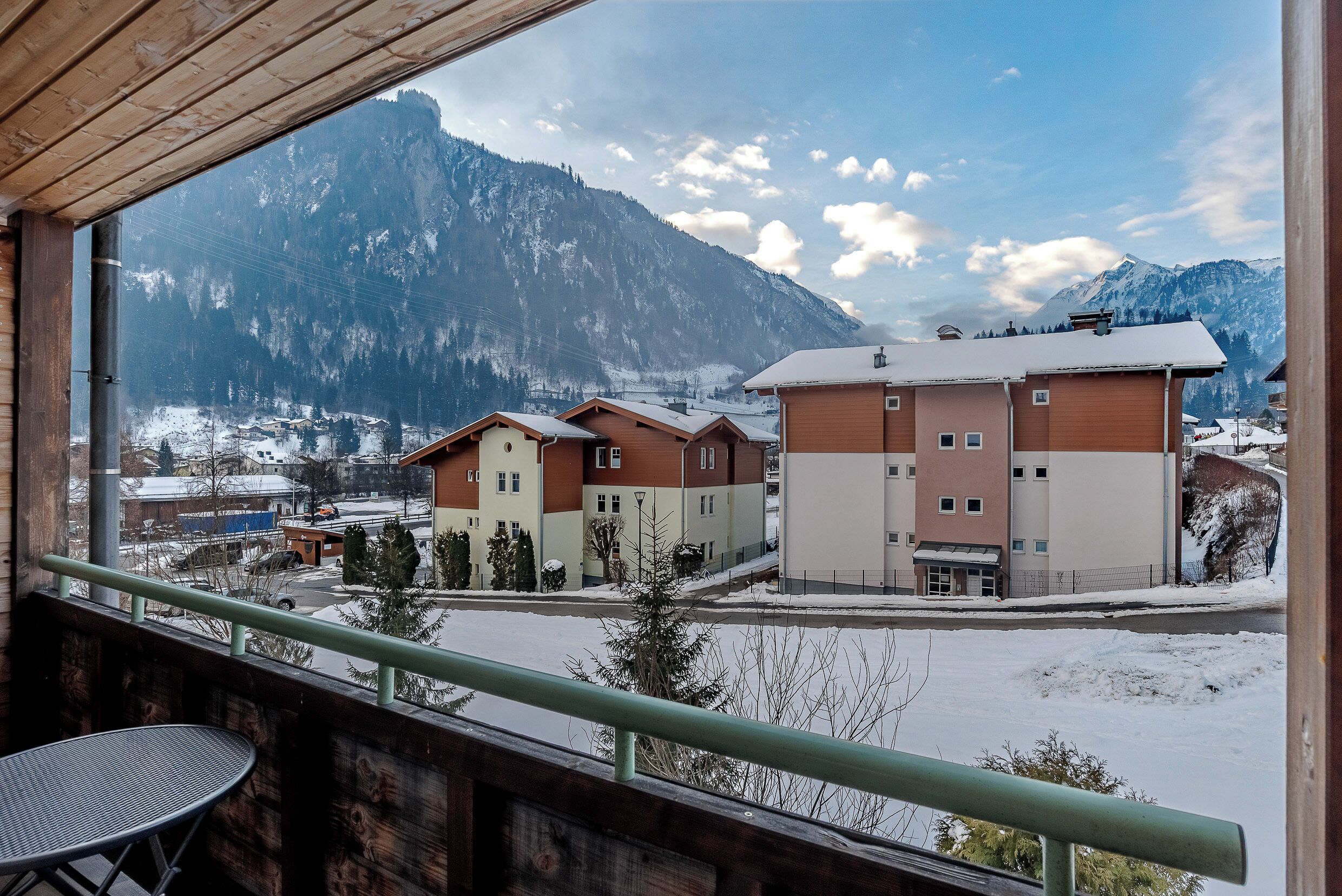 Une vue depuis un balcon donnant sur un paysage montagneux enneigé, avec des bâtiments au premier plan.