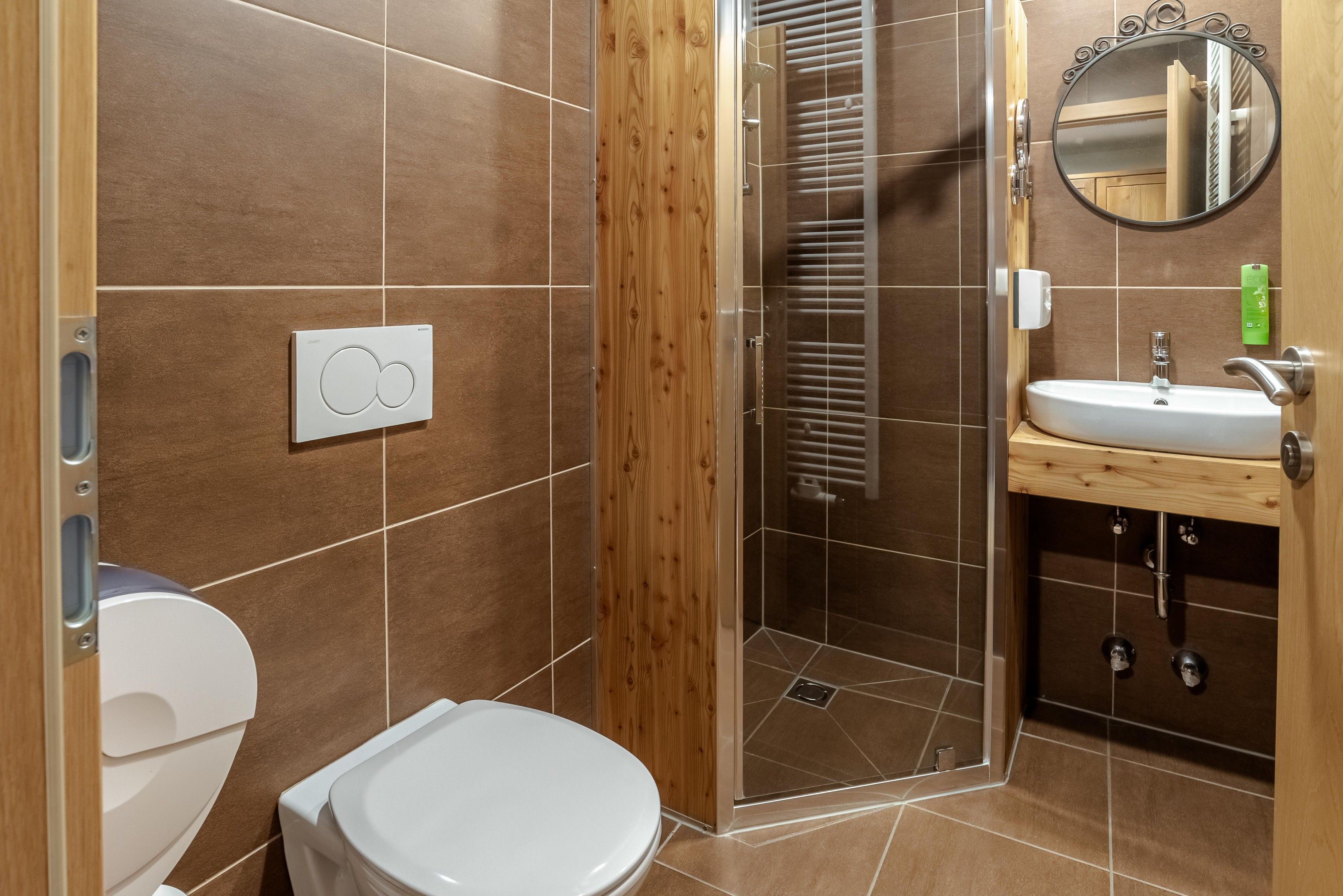 Une salle de bain comprenant des toilettes, un espace douche et un lavabo avec un miroir.