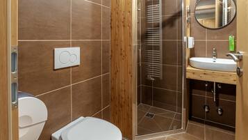Un baño con inodoro, cabina de ducha y lavamanos con espejo.