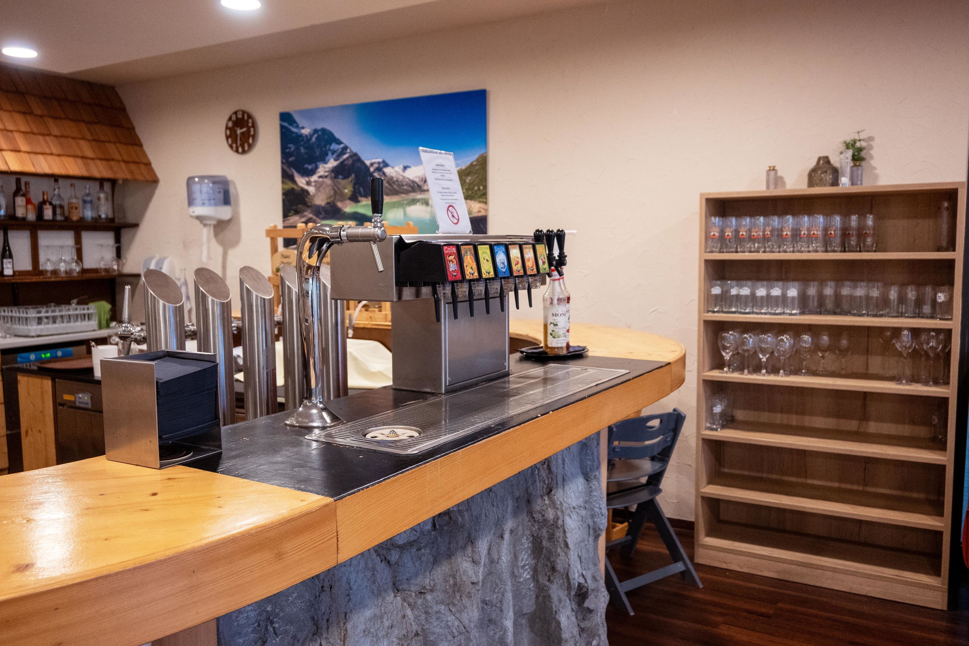 A bar area with a coffee machine, shelves with bottles, and a wine glass display.