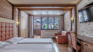 A hotel room with a bed, a desk, a TV, and a view of the mountains. - Hotel Victoriya (Kaprun)