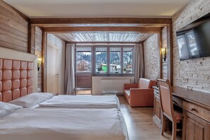 A hotel room with a bed, a desk, a TV, and a view of the mountains. - Hotel Victoriya (Kaprun)