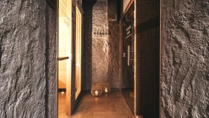 A hallway with stone walls, wooden doors, and a tiled floor. - Hotel Victoriya (Kaprun)