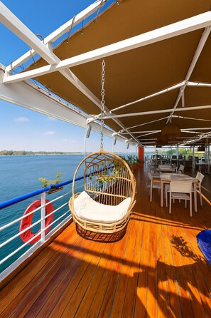 Une terrasse dotée d’une chaise en osier, d’un coin repas et d’une bouée de sauvetage.