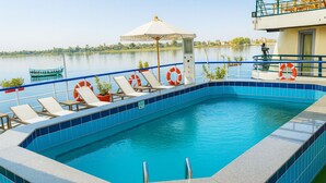 Une piscine aux carreaux bleus, des chaises longues et des bouées de sauvetage.