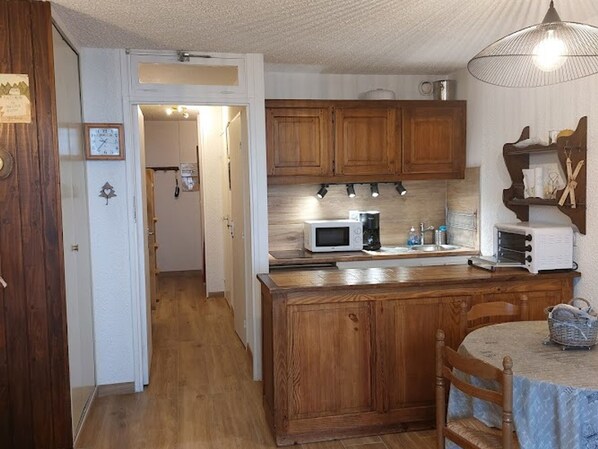 A kitchen with wooden cabinets, a microwave, a toaster, and a dining area with a table and chairs.