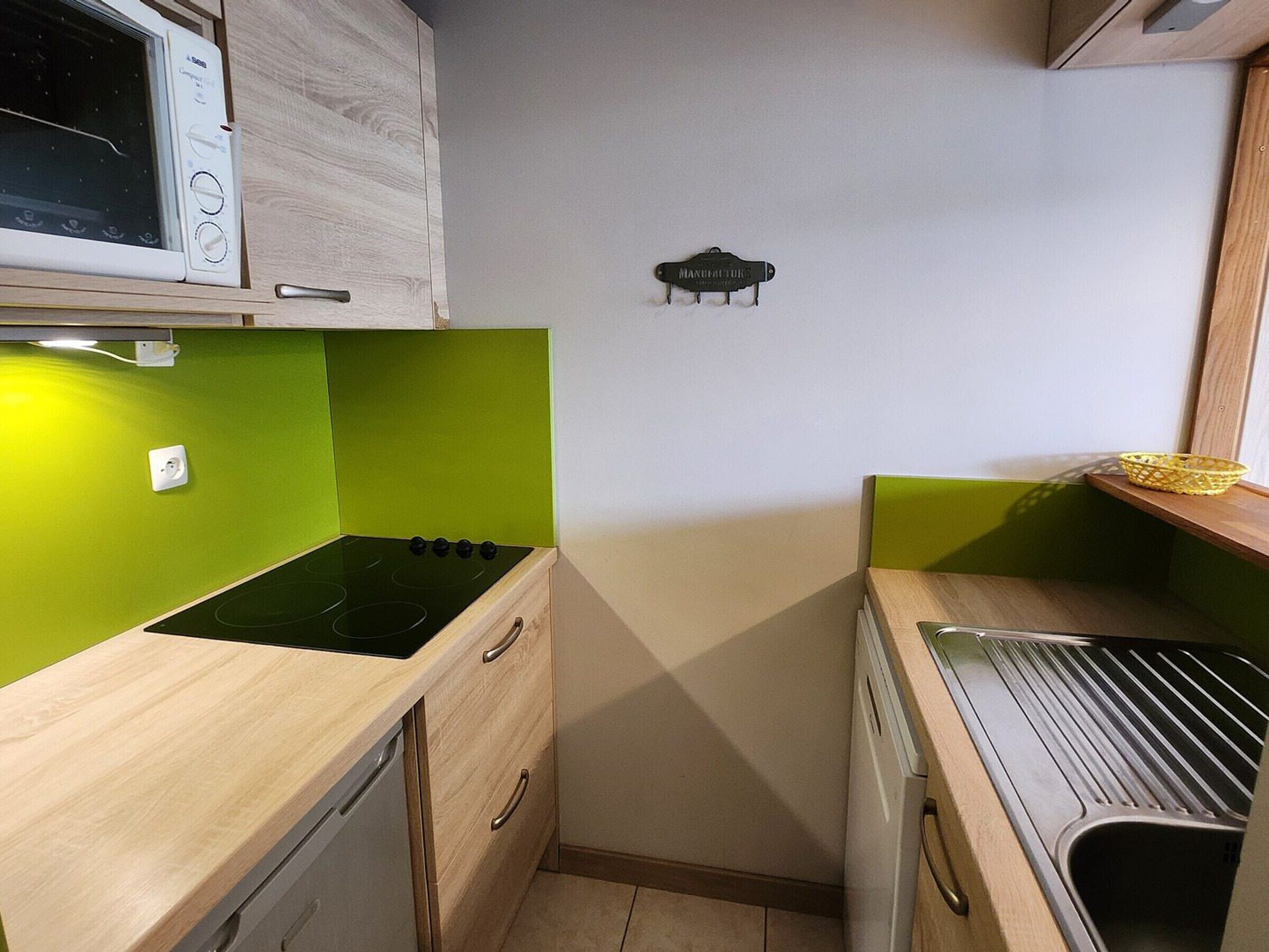 Une petite cuisine équipée d’un four à micro-ondes, d’une cuisinière et d’un évier.