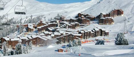A ski resort with multiple chalet-style buildings, ski lifts, and a snowy landscape.