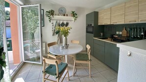 A modern kitchen with a dining area, featuring a round table, chairs, and a clock on the wall.