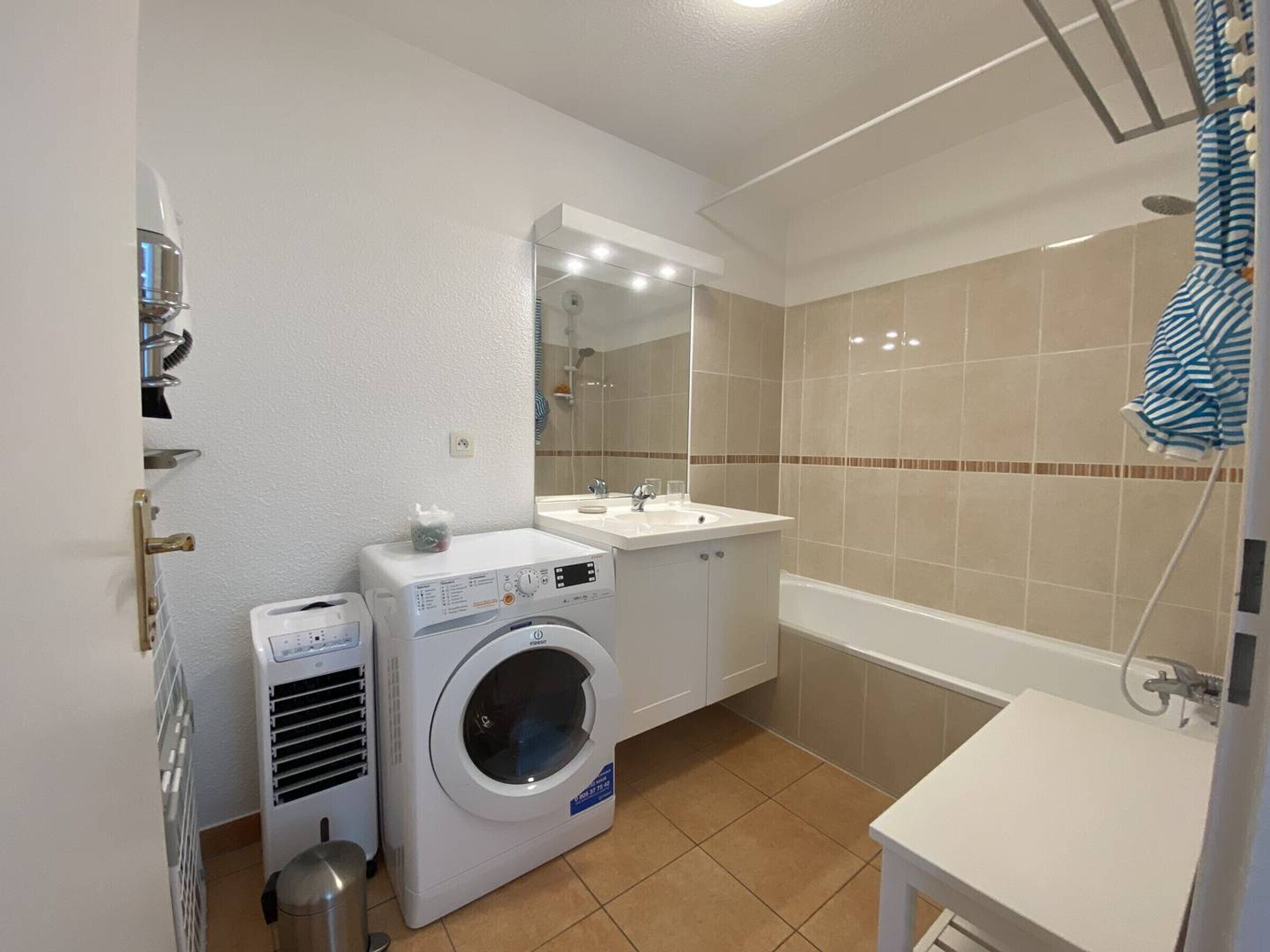 Une salle de bain d’hôtel de taille réduite, équipée d’une machine à laver, d’un sèche-linge et d’une baignoire.
