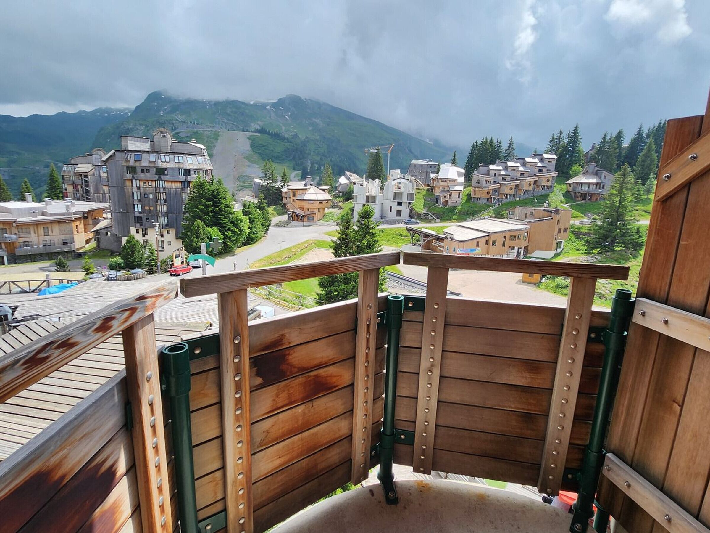 A wooden deck with a view of a mountainous village and buildings.