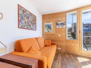 A room with a wooden wall, a framed collage of photos, and a large window with a view of a snowy landscape.