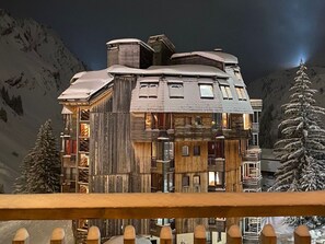 A multi-story wooden building with a sloped roof, large windows, and a balcony.
