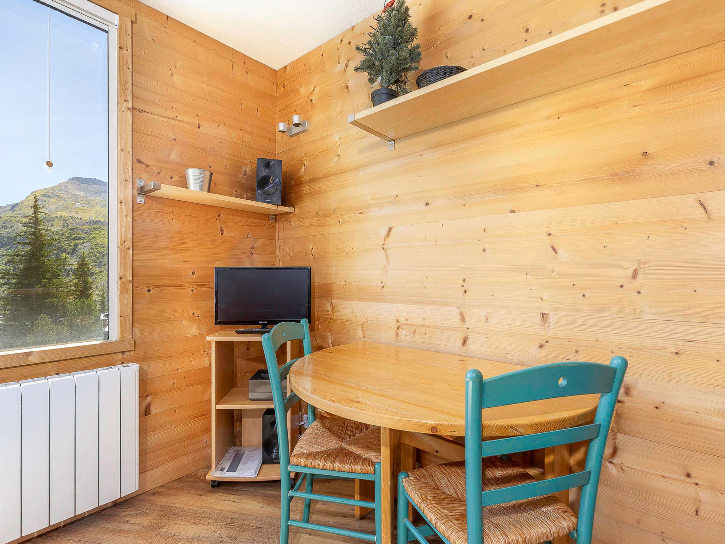 Un intérieur en bois avec une télévision, une table et des chaises.