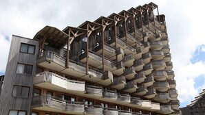Un edificio de varios pisos con balcones en cada planta, que presenta un diseño arquitectónico único con elementos de madera y fachada color beige.