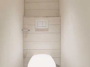 Une salle de bain avec un mur en bois, des toilettes et un interrupteur.