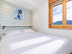 Ein Schlafzimmer mit einem Bett, einem Fenster mit Bergblick und einem an der Wand befestigten Regal mit einer Karte.