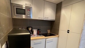 Una cocina compacta equipada con microondas, cafetera y lavavajillas pequeño.