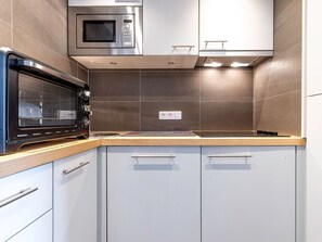 Une cuisine équipée d’un four à micro-ondes encastré, d’une cuisinière et d’un évier.