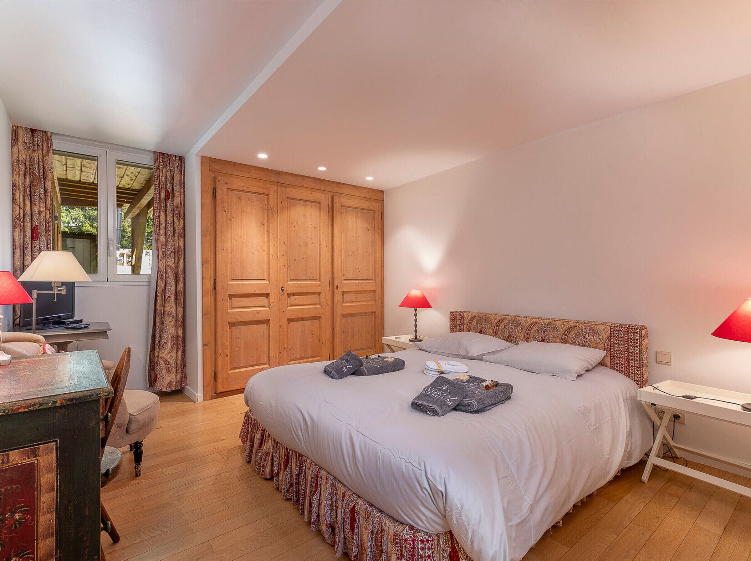 A bedroom with a bed, bedside tables, a desk, and a wardrobe.