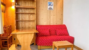 Et hyggeligt rum med trævæg, en rød sofa, et træbord og en træbænk.