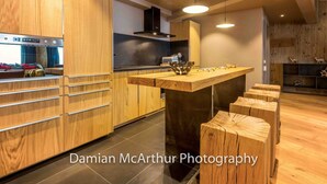 A modern kitchen with wooden cabinetry, a central island, and pendant lighting. - Exceptional loft for 12, ski-in access, sauna & hammam (Avoriaz)
