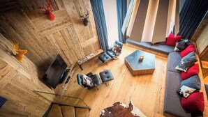 A modern living room with a wooden floor, leather sofas, and a glass coffee table. - Exceptional loft for 12, ski-in access, sauna & hammam (Avoriaz)