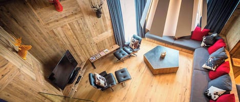Un salon moderne avec un plancher en bois, des canapés en cuir et une table basse en verre.