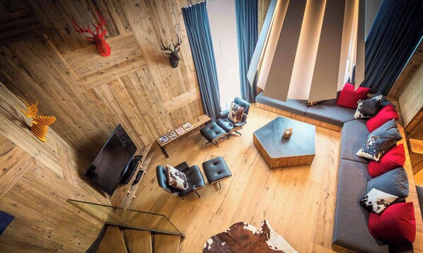 Un salon moderne avec un plancher en bois, des canapés en cuir et une table basse en verre.